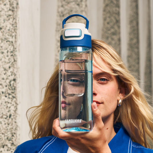 Vrouw die een gevulde Kambukka waterfles voor haar hoofd houdt