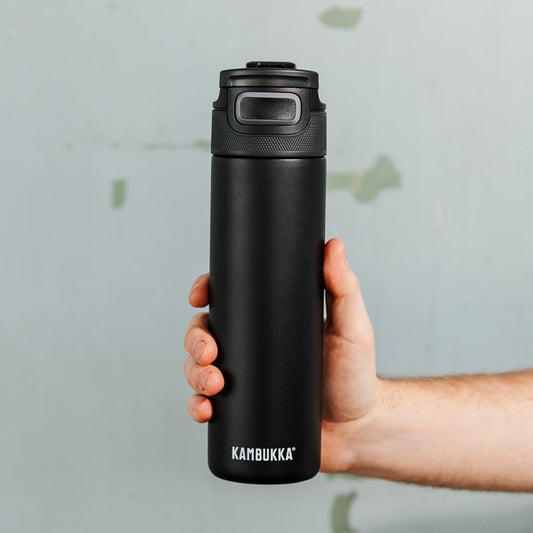 Een foto van een hand die een zwarte Elton Insulated 600 ml van Kambukka vastheeft